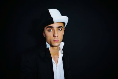 Portrait of man wearing hat against black background