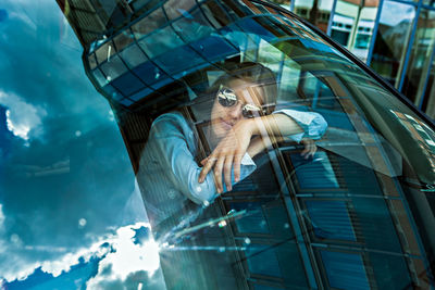 Teenage girl wearing sunglasses sitting in car seen through windshield