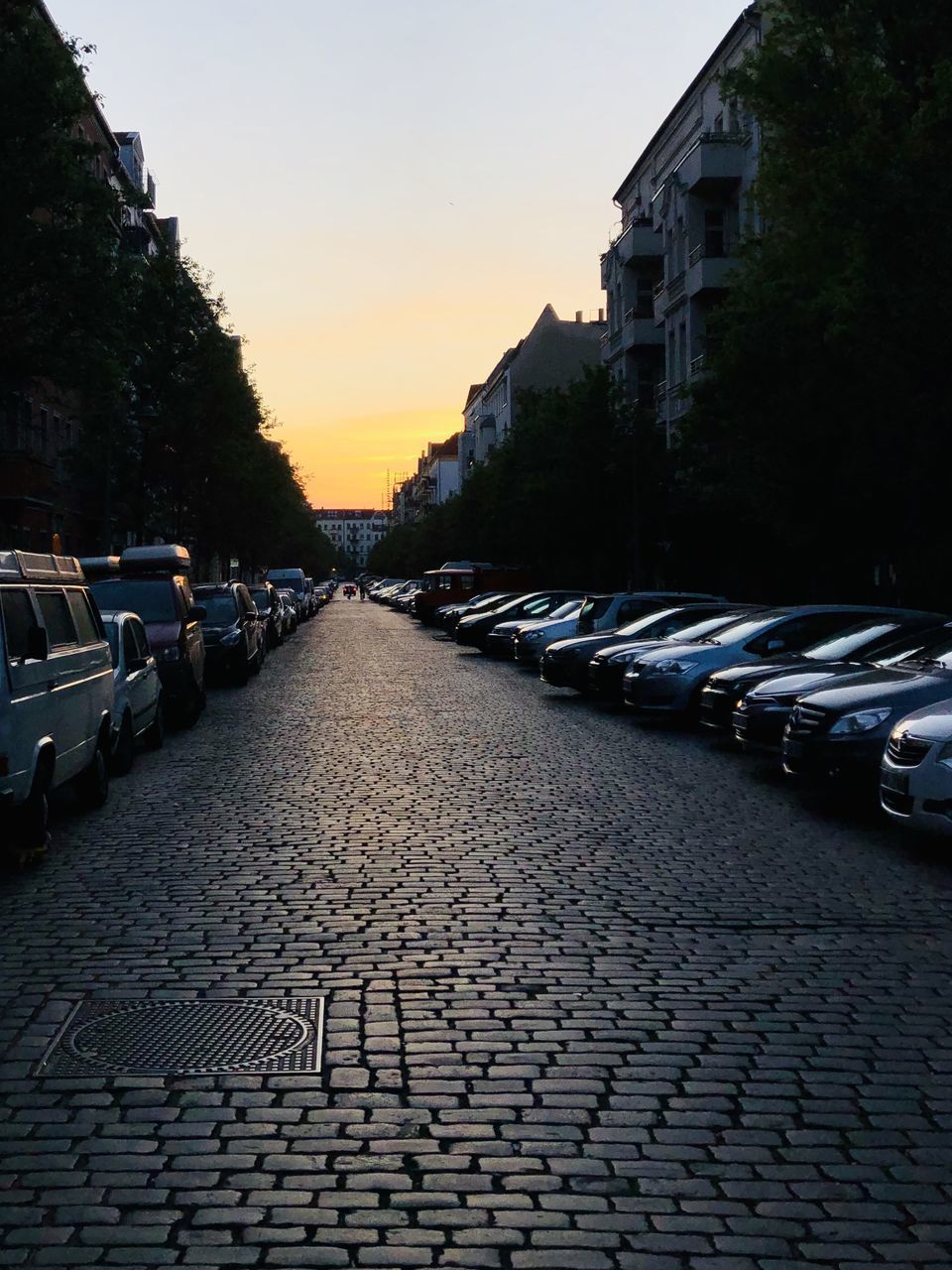 STREET AMIDST BUILDINGS IN CITY DURING SUNSET