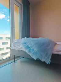 Rear view of woman sitting on bed at home