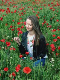 Beautiful young woman on red poppy flowers in land