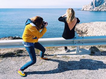 Friends photographing by sea