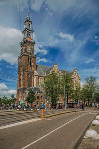 Street with old church steeple and blue sky in amsterdam. the netherland capital full of canals.