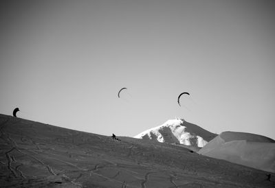 People on snowcapped mountain against clear sky