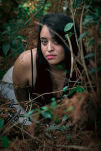 High angle portrait of young woman sitting in forest