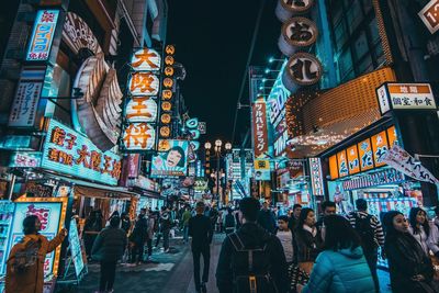People on illuminated street at night in city