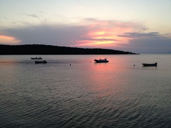 Boats in sea at sunset