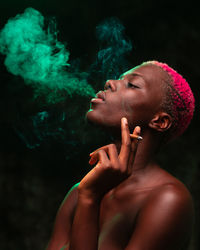 Side view of shirtless girl looking away against black background