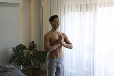 Shirtless young man meditating at home