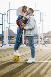 Couple touching her noses on a basketball court. girl on the basket ball. happy girlfriend