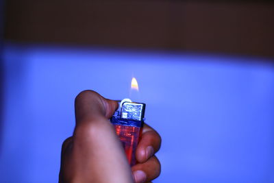 Cropped hand holding lit cigarette lighter