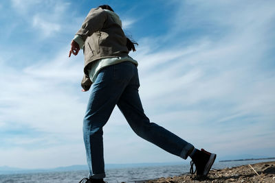 Rear view of young woman on beach against sky