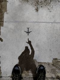 Reflection of man gesturing towards airplane in puddle on road