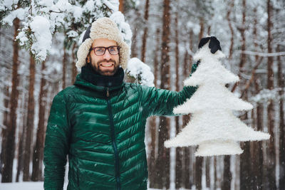 Portrait of smiling man standing by plants during winter