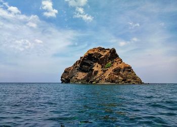 Rock formation in sea against sky