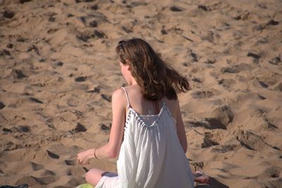 Rear view of woman sitting on sand at beach