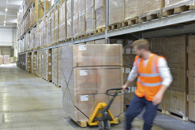Man in factory hall using pallet jack