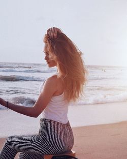 Side view of woman sitting on beach