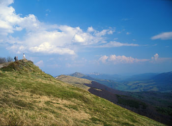 People hiking on mountain against sky