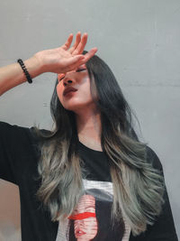 Close-up of young woman standing against wall