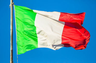 Low angle view of flag against blue sky