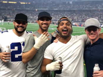 Excited friends with drinks standing in stadium