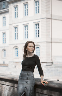 Young woman standing against railing in city