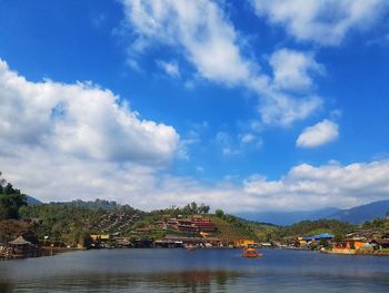 Scenic view of river by buildings against sky