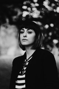 Portrait of woman standing against black background