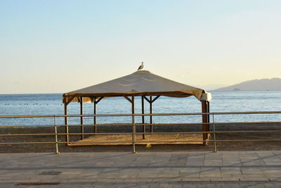 Gazebo on beach against clear sky