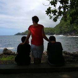 Rear view of father and son looking at sea