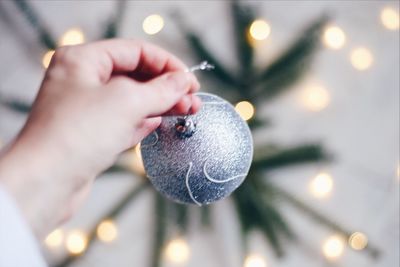 Close-up of human hand holding christmas bauble at home