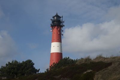 Low angle view of lighthouse by building against sky