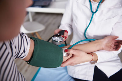 Doctor taking blood pressure of woman in medical practice