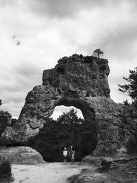 People on rock formation against sky