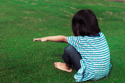 Rear view of woman sitting on grassy field