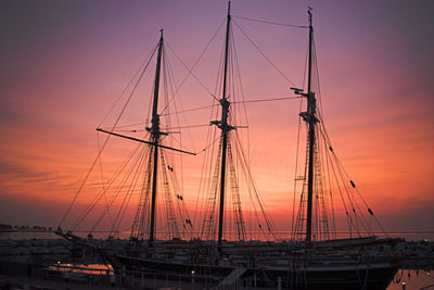 Sailboats moored at harbor during sunset