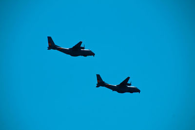 Low angle view of airplane against clear blue sky