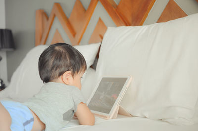 Rear view of boy using mobile phone at home