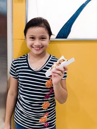 Portrait of smiling girl standing against wall