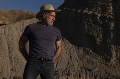 Adult man in cowboy hat on desert against mountain. almeria, spain