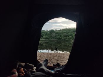 Low section of people relaxing on window against sky