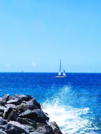 Sailboat in sea against blue sky