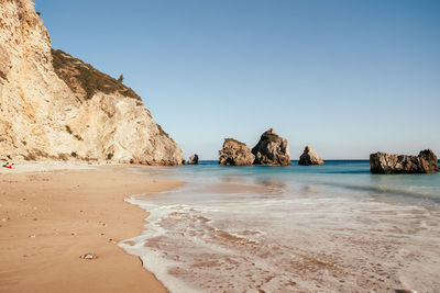 Scenic view of beach against clear blue sky