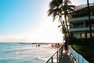 People walking by building against sea at beach