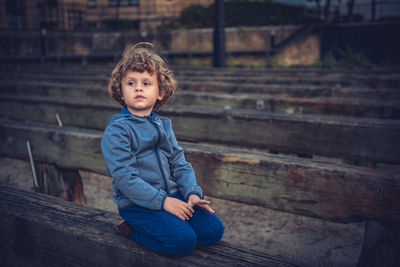 Portrait of boy sitting on wood