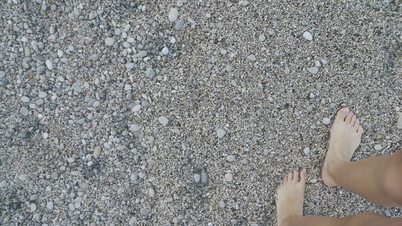 low section, person, lifestyles, personal perspective, leisure activity, human foot, high angle view, standing, barefoot, part of, shoe, unrecognizable person, day, outdoors, textured, beach
