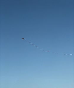 Low angle view of kite flying against clear blue sky