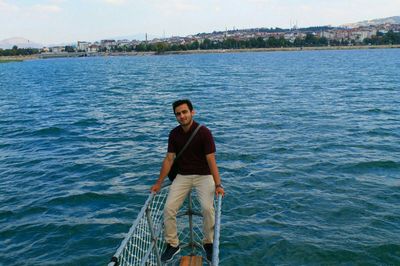 Portrait of man sitting on railing over sea