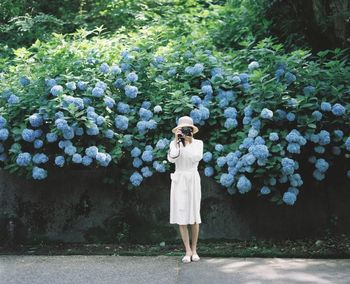 Full length portrait of woman standing against trees